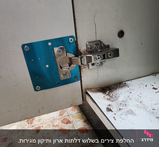 ציר מתכת על דלת ארון מטבח עם לוח חיזוק כחול